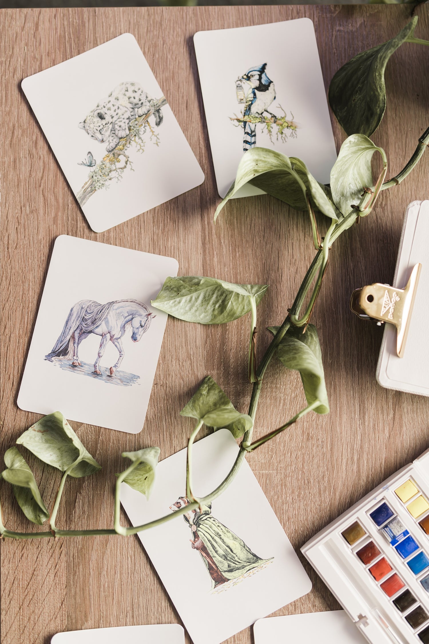 A collection of Julia Hope’s whimsical animal cards laid out on a table, featuring watercolor illustrations of bunnies, woodland creatures, and nature-inspired scenes.